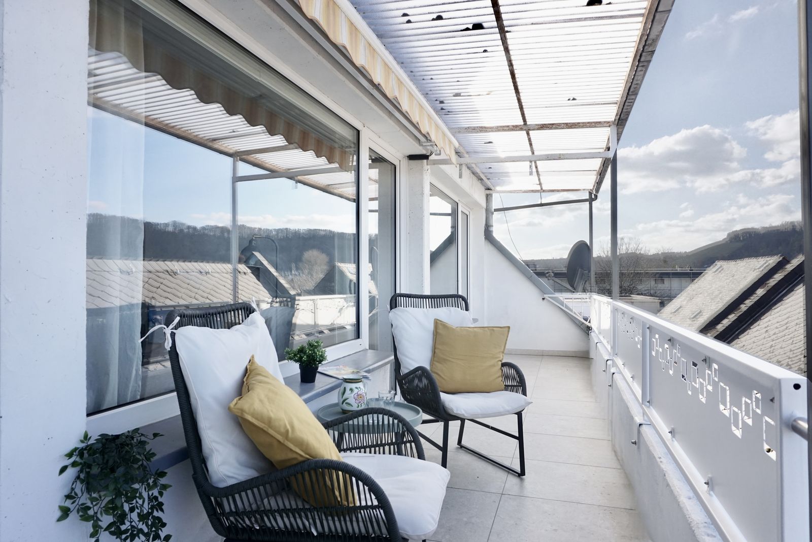 Balkon mit zwei Loungesesseln und Blick über die Dächer