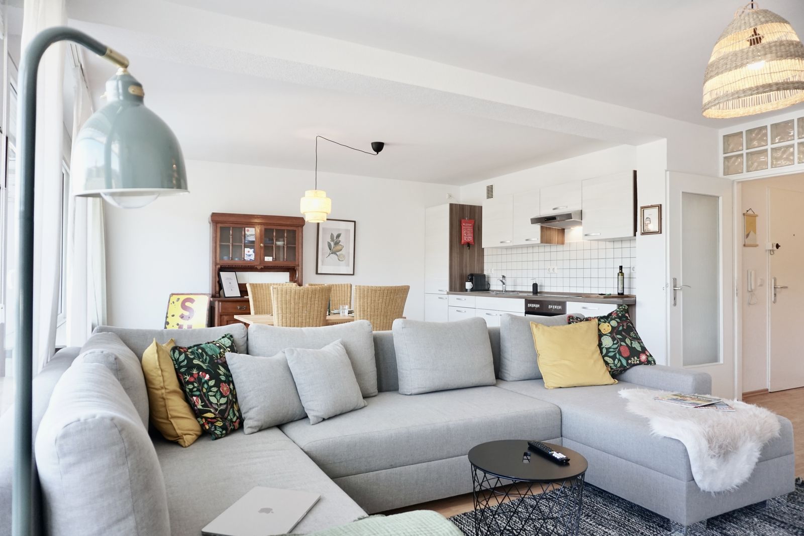 Wohnzimmer mit grauem Ecksofa und Esstisch im Hintergrund